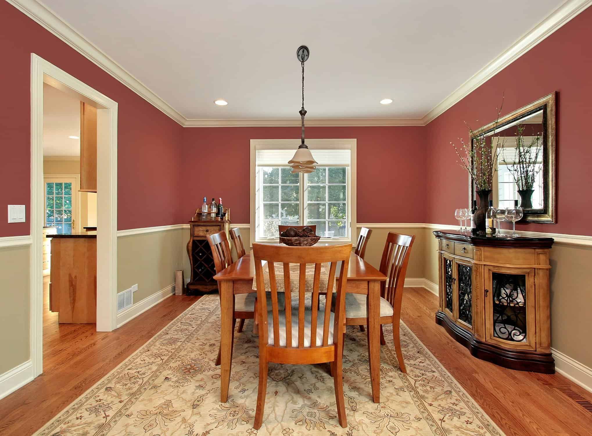 Elegant dining room with rich cranberry red walls and cream wainscoting painted by CYR Painting Services, featuring white crown molding, hardwood floors, and contrasting two-tone color scheme