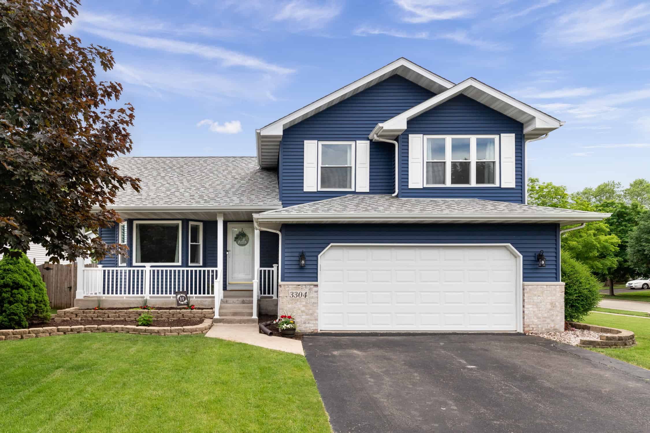 Exterior of a suburban home with blue siding, a white front porch