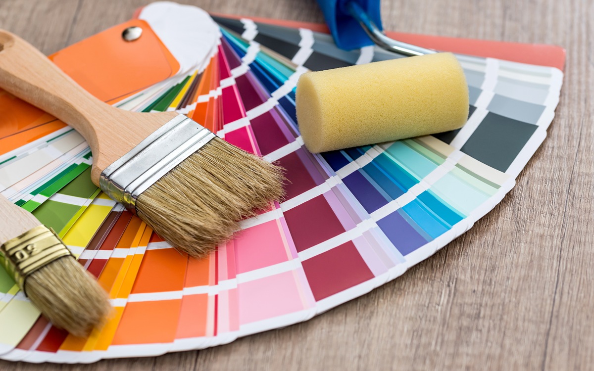 Paint brushes on colour swatch, wooden table background