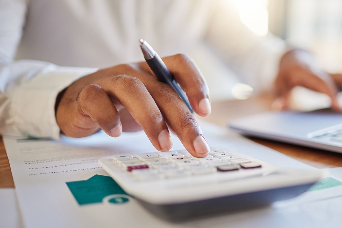 Finance, accounting and fintech, a man on a computer and calculator working out his business budget strategy. Businessman at his office desk, laptop, money management and financial investment online.