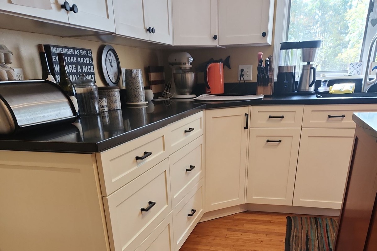 Bright White Shaker Kitchen Cabinet Painting Project Beautifully repainted cream shaker style kitchen cabinets and drawers with black countertops.