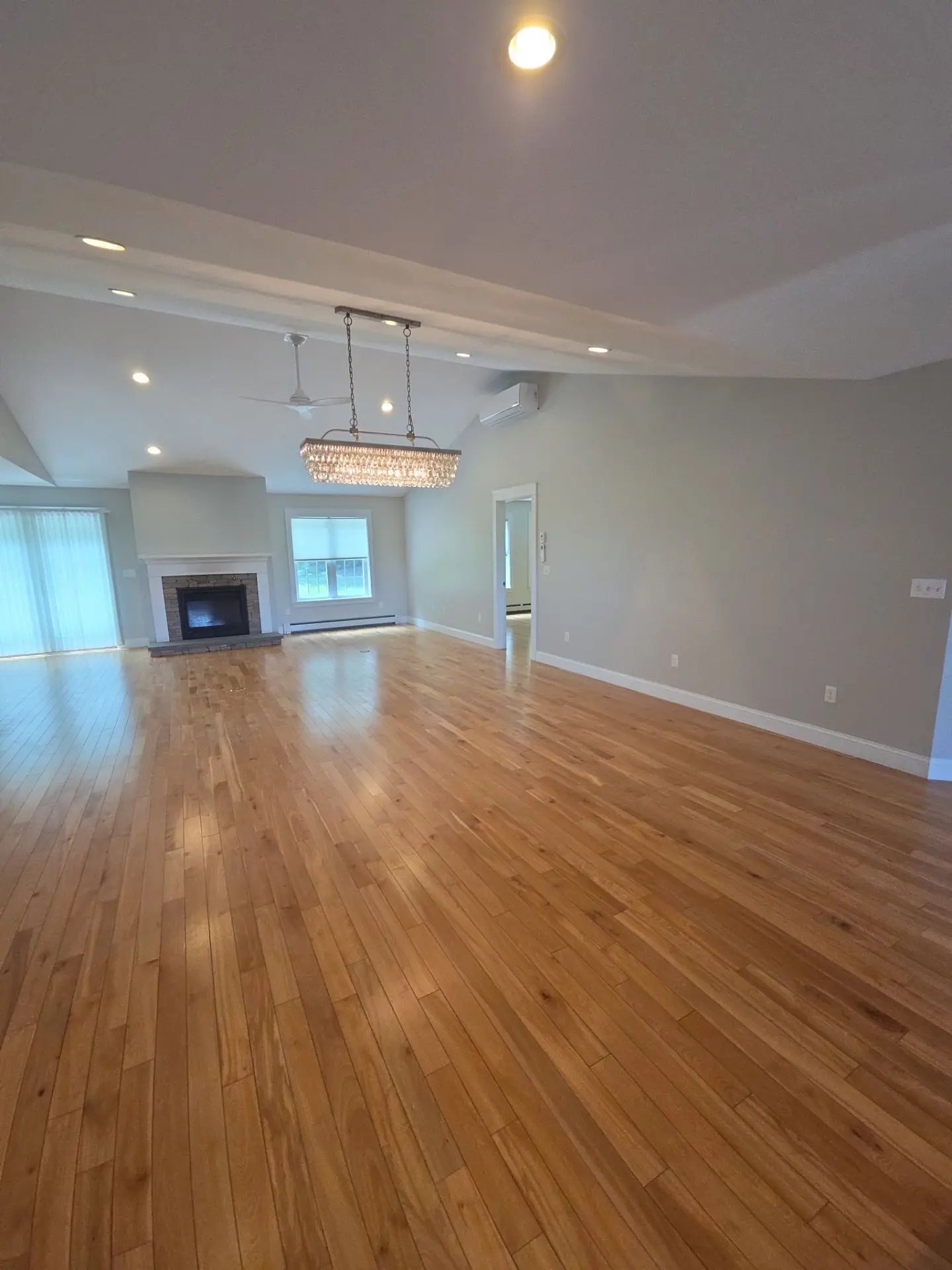 Spacious Living Room Interior Painting A large, freshly painted residential living room with light gray walls, a fireplace, and hardwood floors.