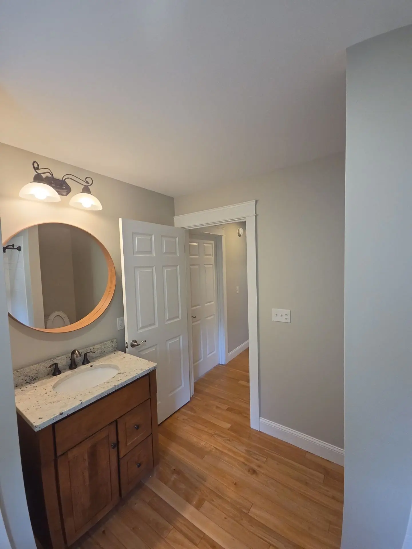 Modern Bathroom Interior Painting A newly painted residential bathroom featuring a vanity, round mirror, and light gray walls.