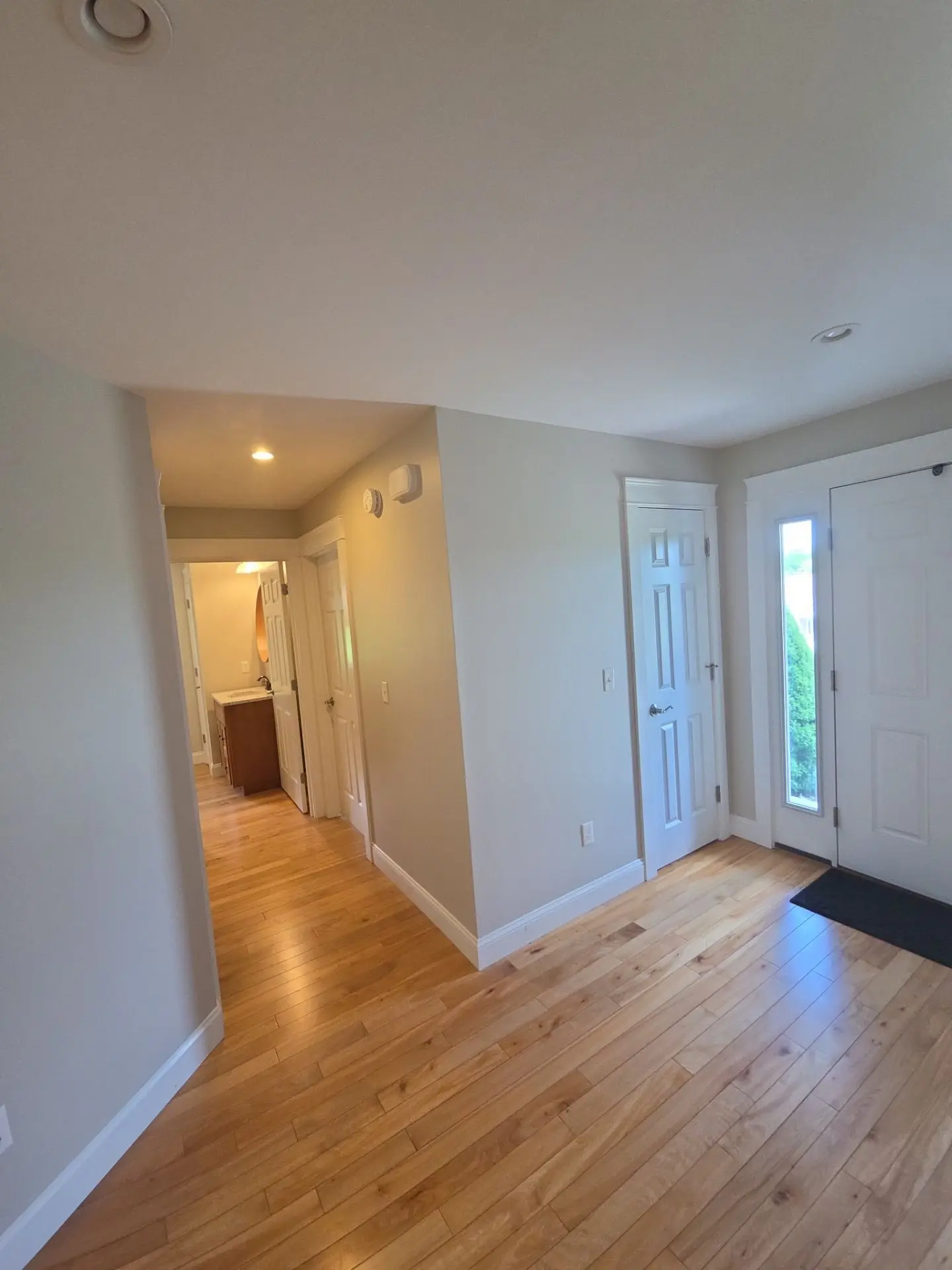 Residential Hallway Interior Painting Project A bright, newly painted residential hallway with light gray walls, white trim, and polished hardwood floors.