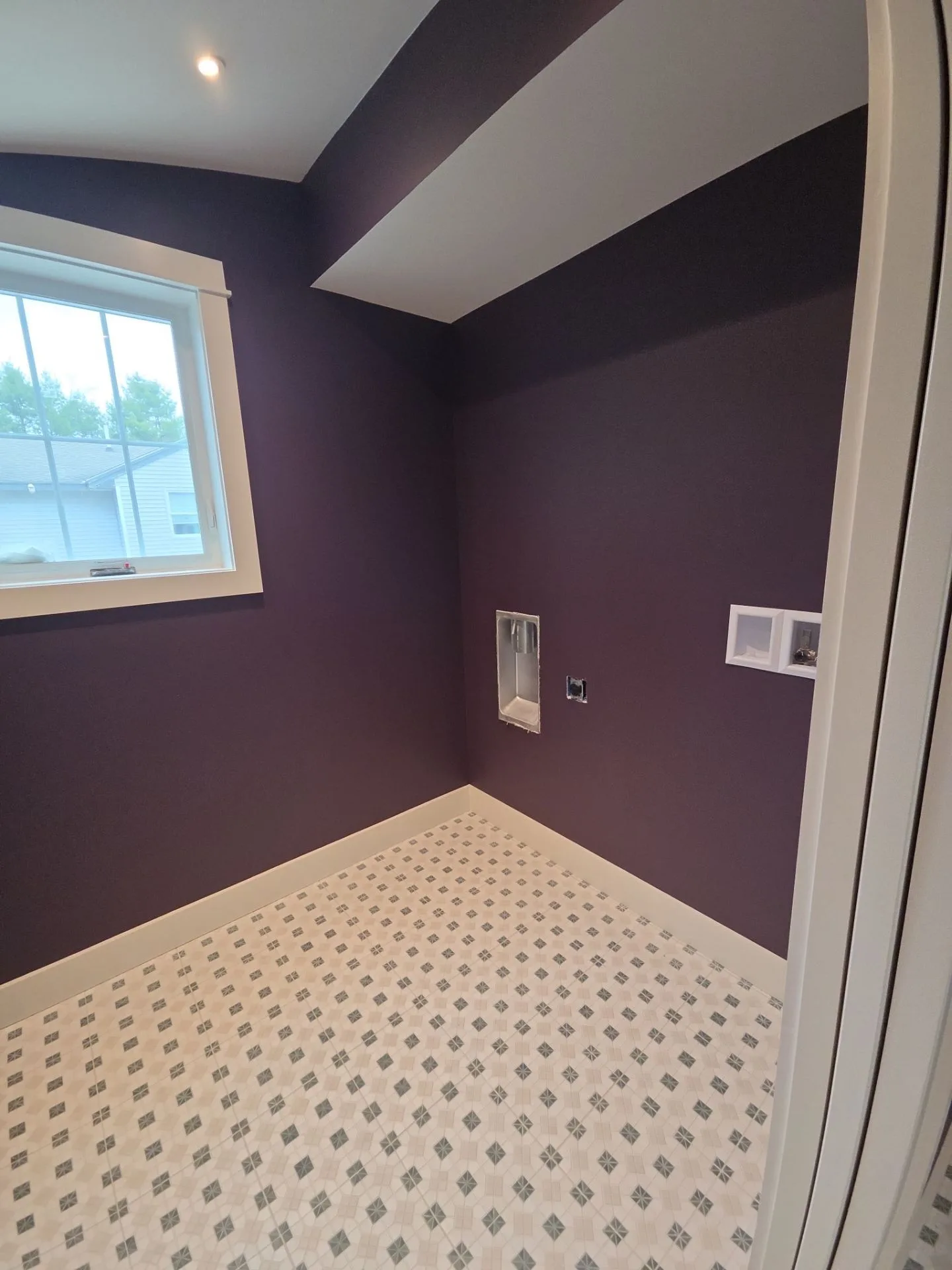 Plum Purple Bathroom Walls Plum-purple painted bathroom walls with white ceiling, angled soffit, window, electrical outlets, and patterned tile
