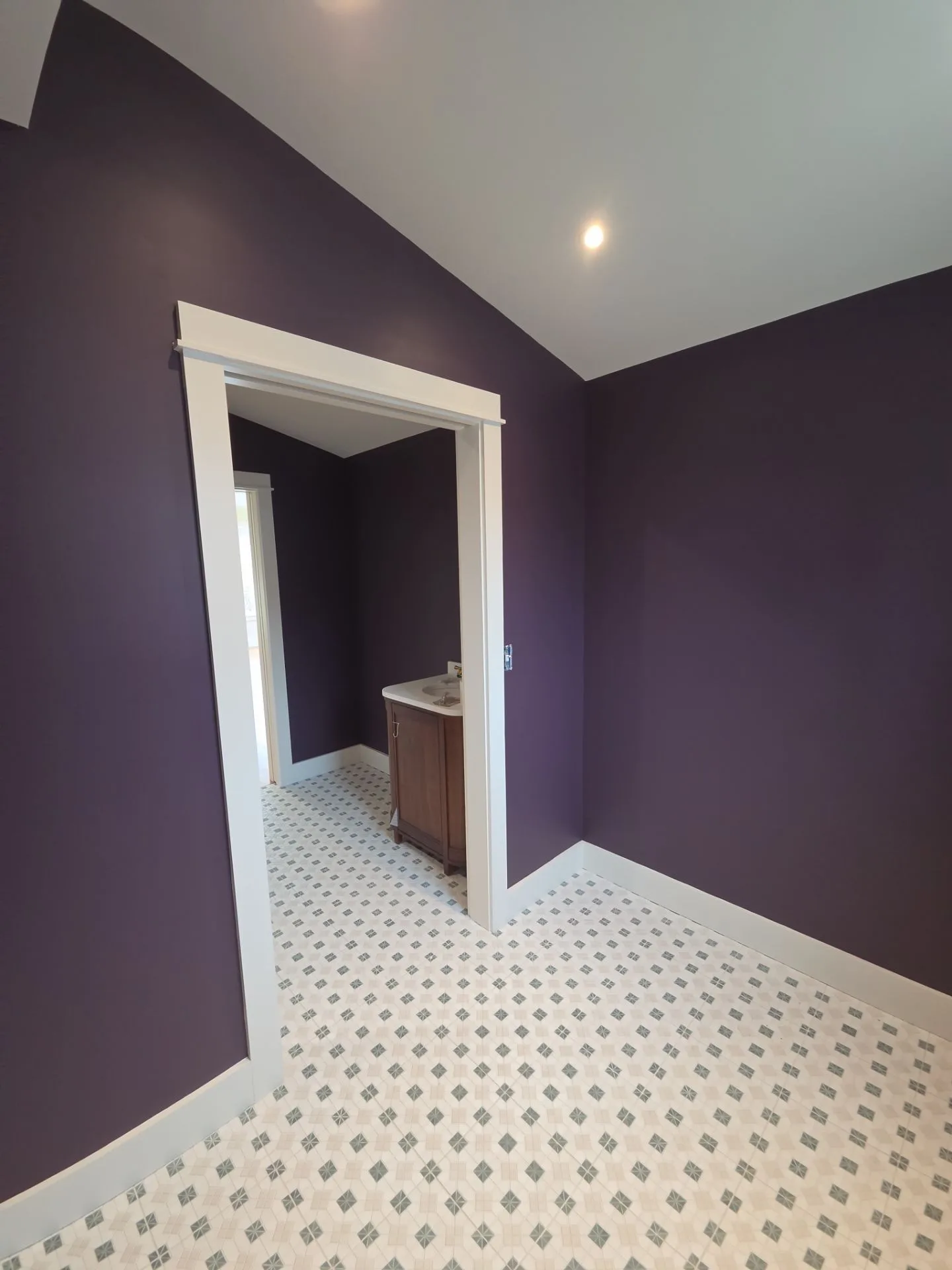 Plum Purple Bathroom Walls Plum-purple painted bathroom walls with white trim doorway, gray-and-white patterned tile flooring, and recessed ceiling
